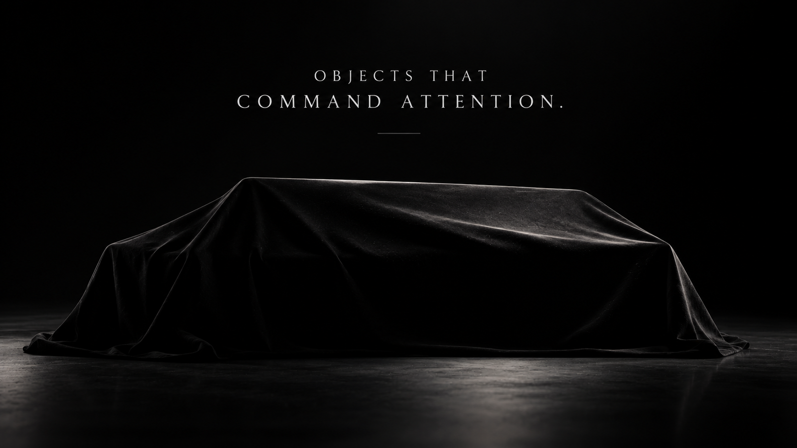 A mysterious long object concealed beneath black fabric in a dark studio.
